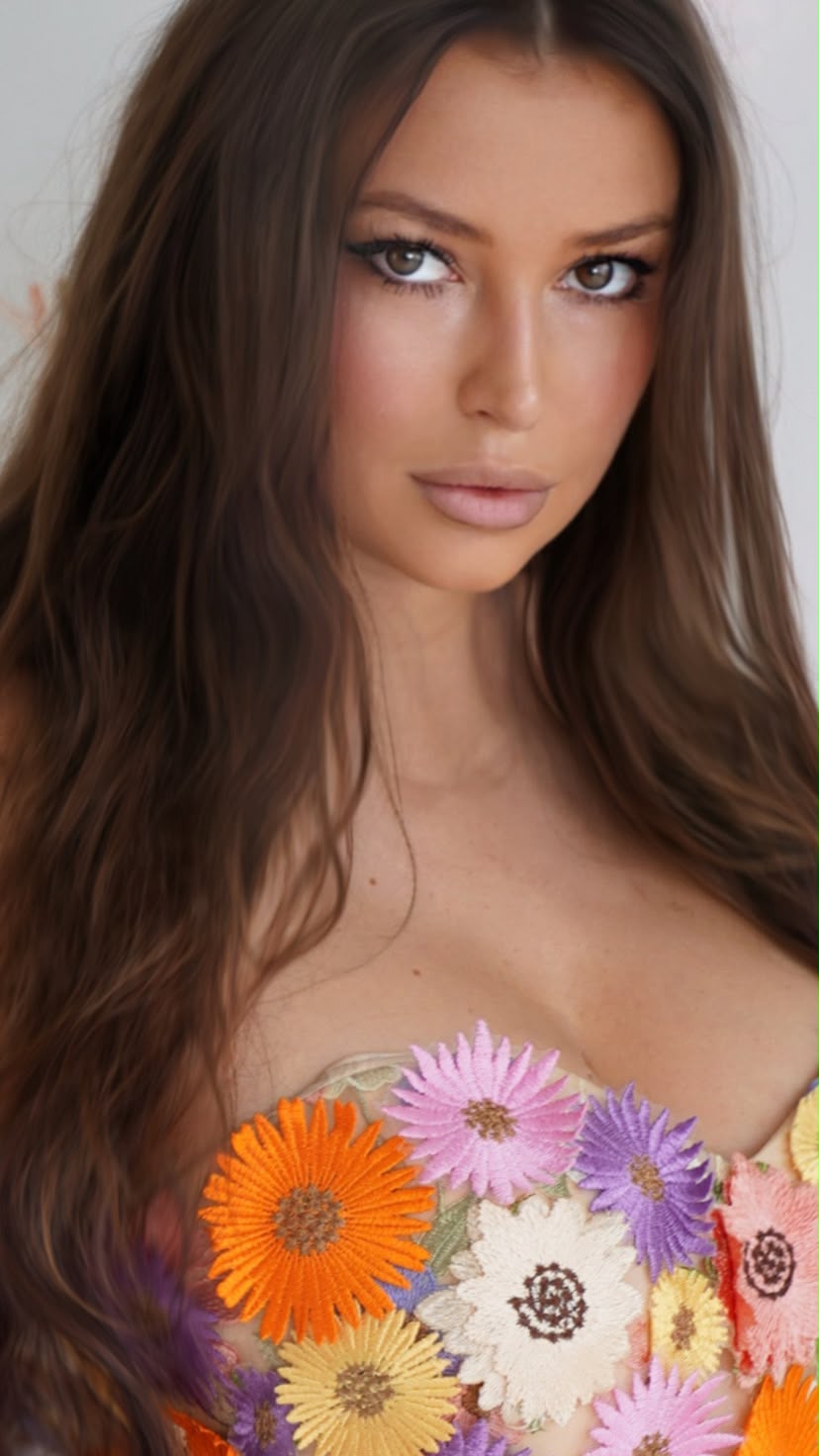 Close portrait of Lilia Mai wearing a bustier embroidered with colourful flowers.